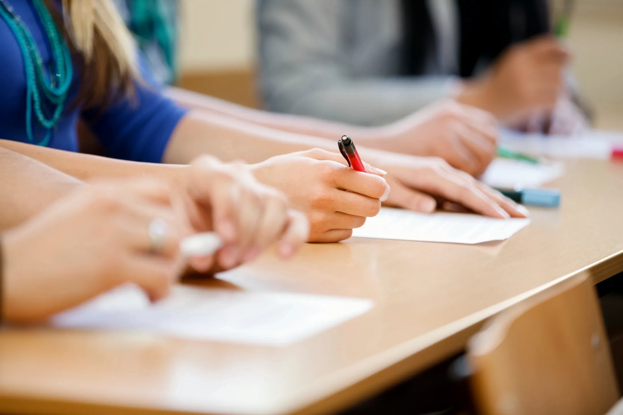 Students writing at a classroom desk